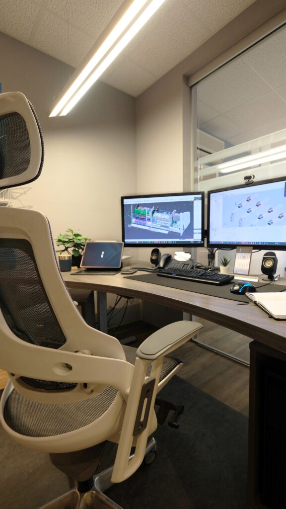 Ein ergonomischer Stuhl vor einem Schreibtisch mit eingeschalteten Monitoren