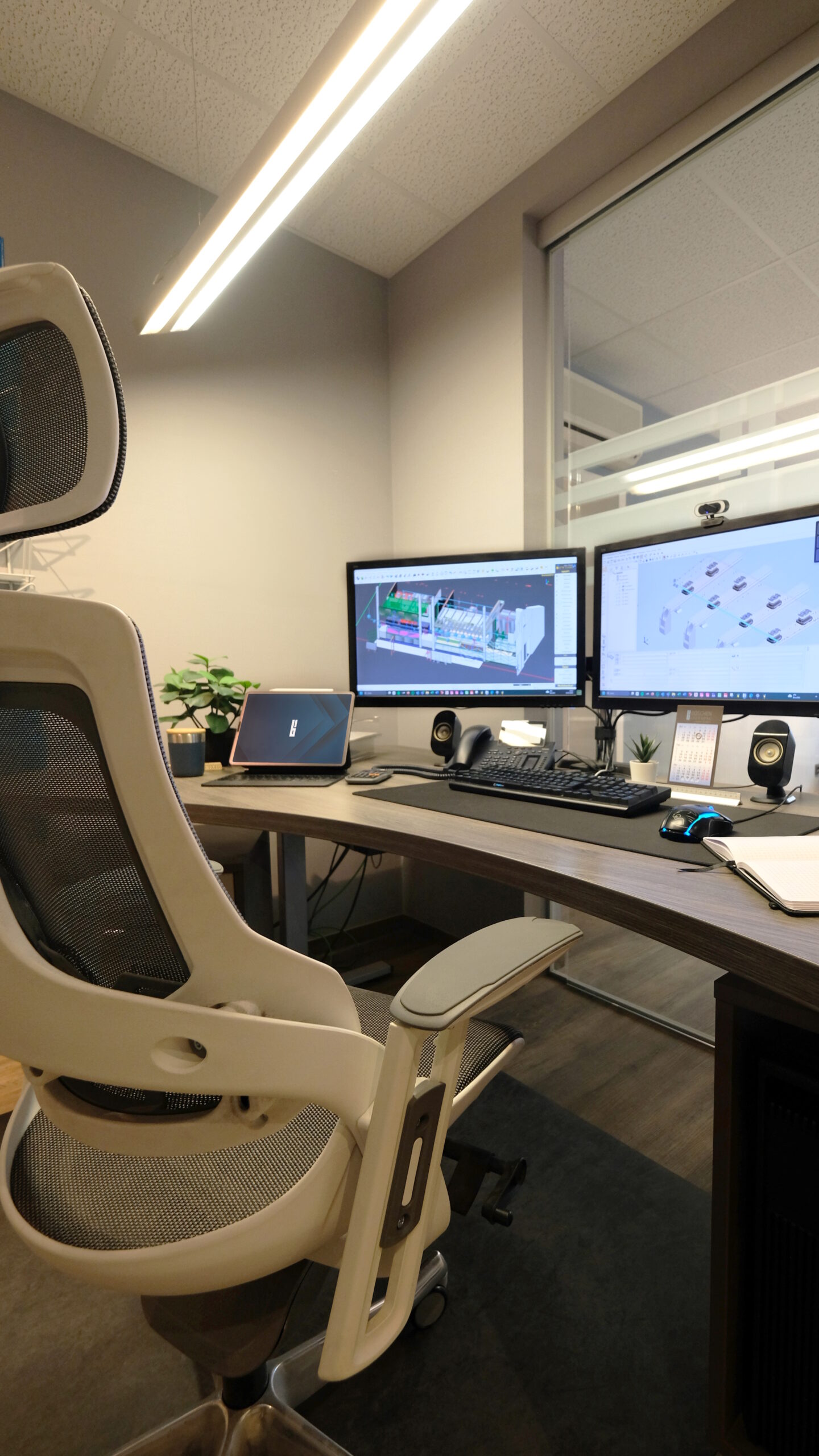 Ein ergonomischer Stuhl vor einem Schreibtisch mit eingeschalteten Monitoren